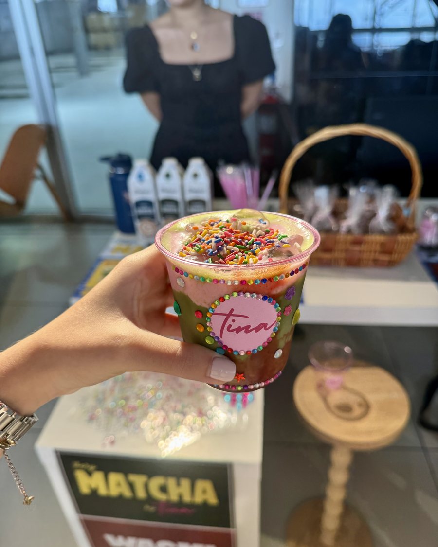 Vaso de VeryMatcha con confeti de colores frente al cartel del pop-up