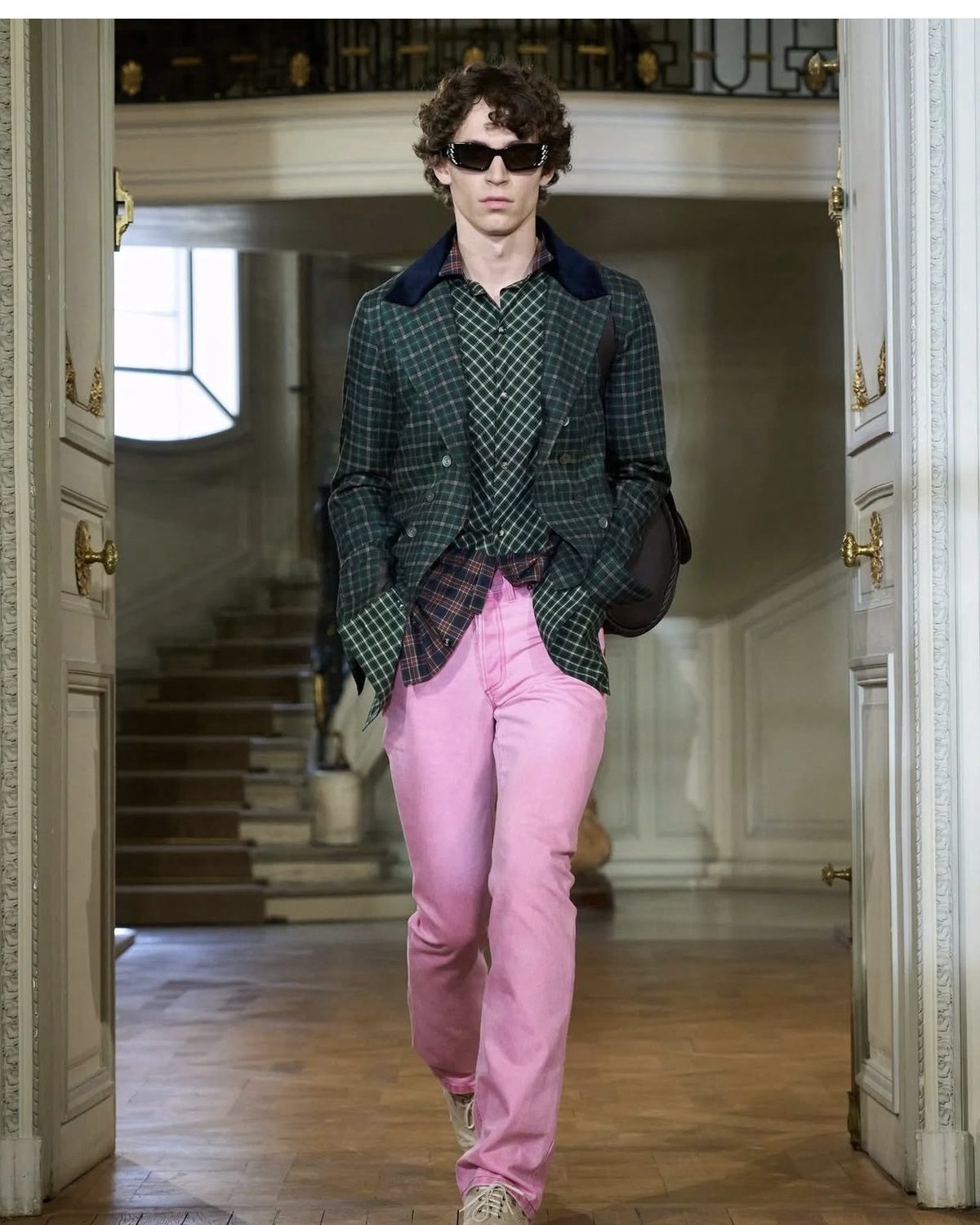 Modelo con blazer de tartán verde y jeans rosados en un desfile de primavera 2027