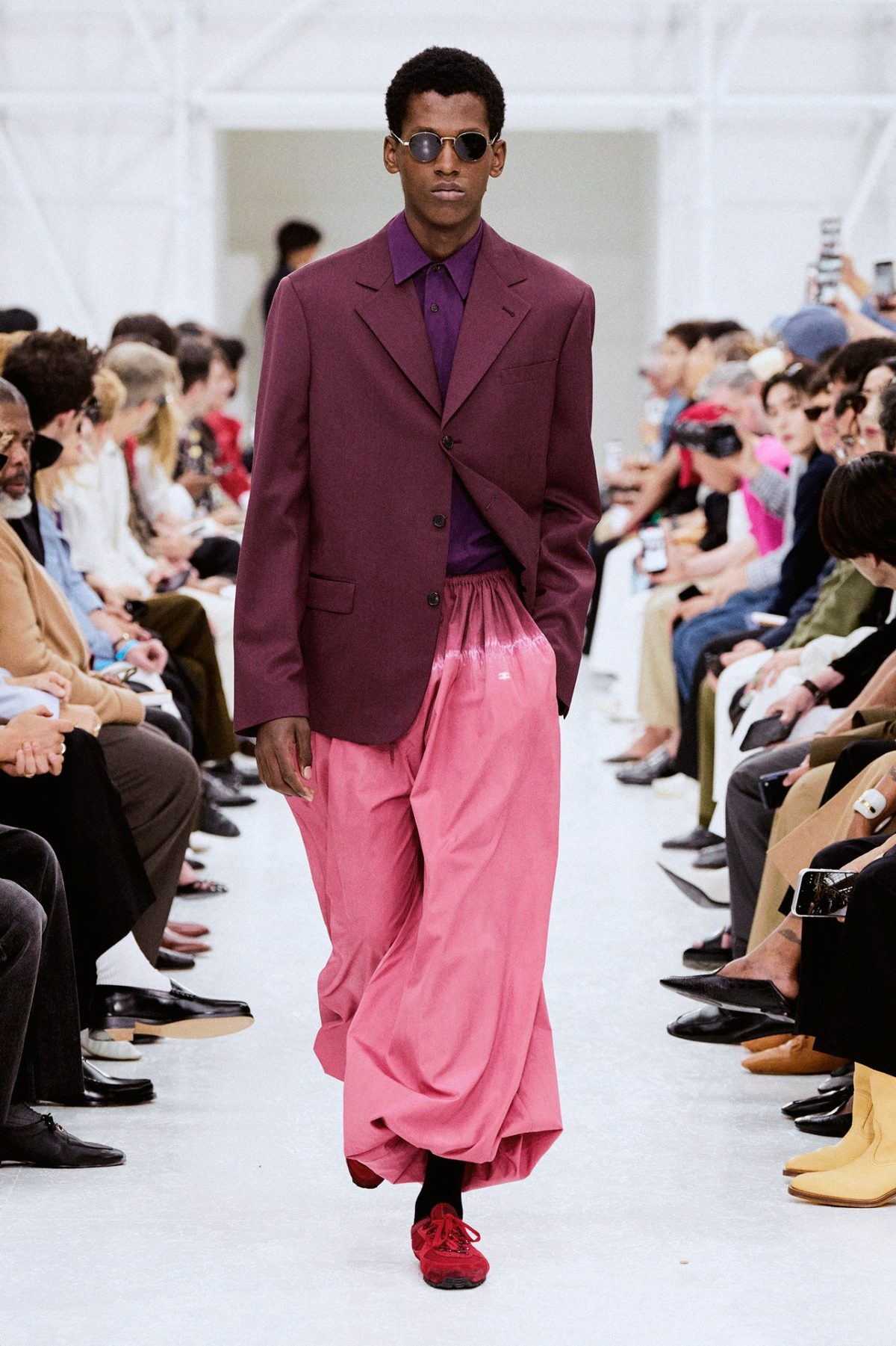 Modelo de Celine con blazer burdeos, camisa morada y pantalón rosa degradé