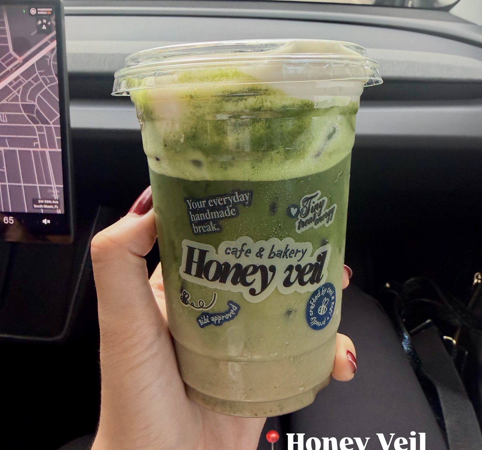 Matcha helado de Honey Veil sostenido en la mano dentro del carro, con la calle de Miami al fondo