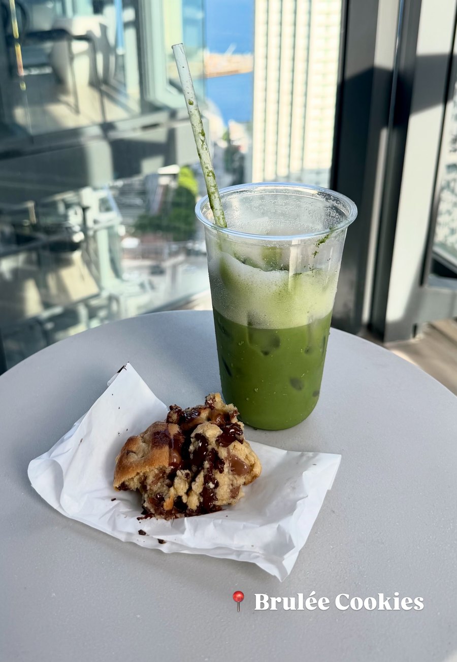 Matcha de Brulée Cookies con una galleta, frente a la ventana de un piso alto de Miami
