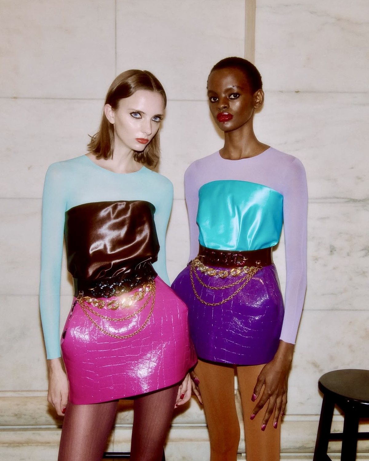 Dos modelos con tops transparentes y minifaldas de croco laqueado en fucsia y morado