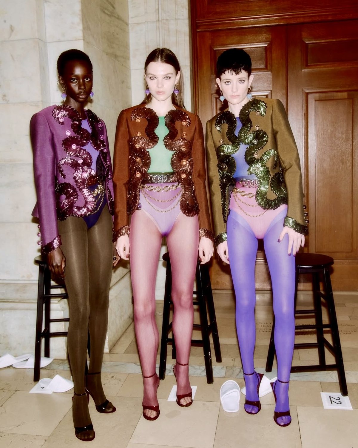 Tres modelos con chaquetas bordadas con apliques en morado, marrón y verde oliva
