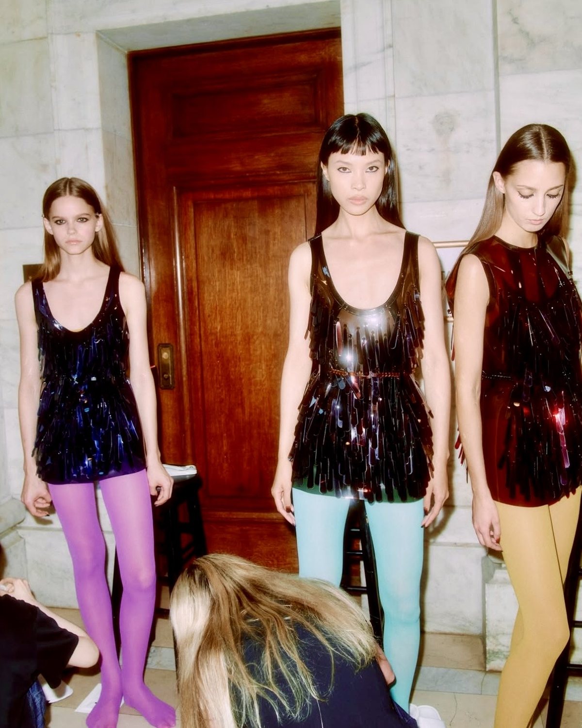 Tres modelos con minivestidos de lentejuelas alargadas y medias de colores