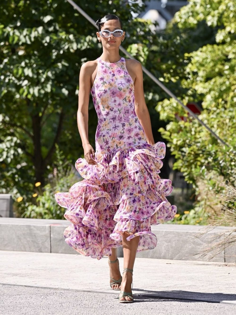 Modelo con vestido floral lila de volantes y lentes de sol blancos